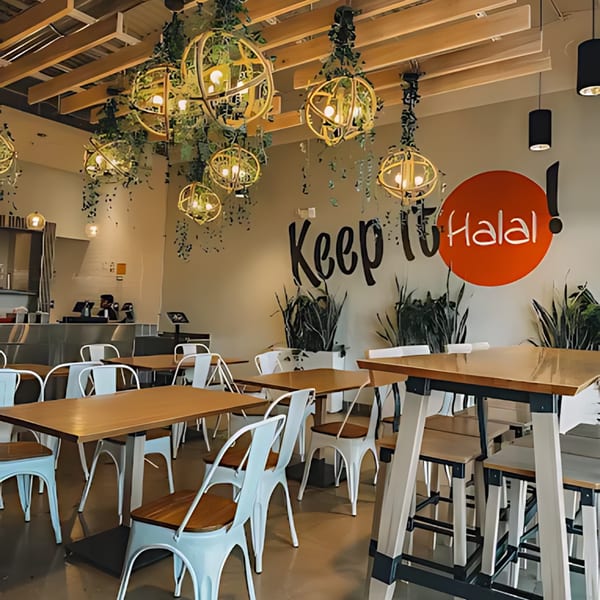 Halal Bros restaurant interior with tables, chairs, and a wall mural that reads "Keep it Halal!"