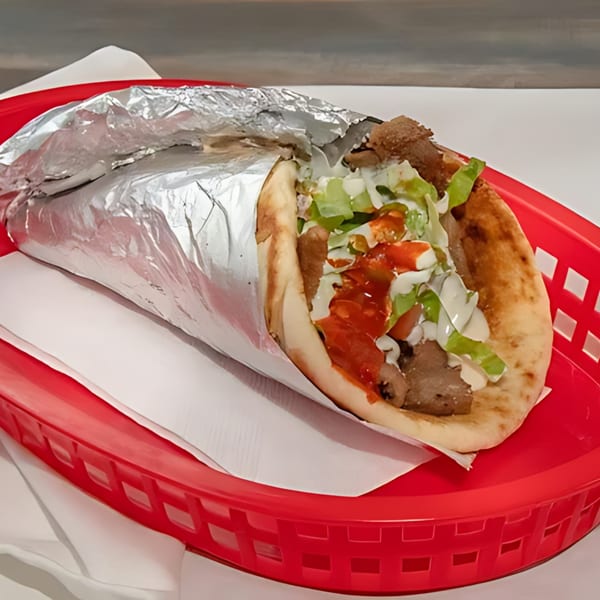 Halal Bros gyro with meat, lettuce, and sauces, partially wrapped in foil, in a red basket.