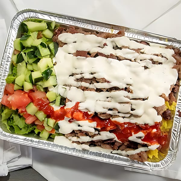 Halal Bros' large platter of halal meat, rice, salad, white sauce, and red sauce in a foil container.