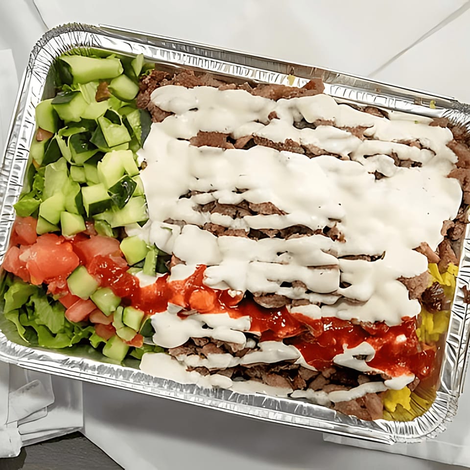 Halal Bros' chicken and lamb over rice with white and red sauce, and a side salad.